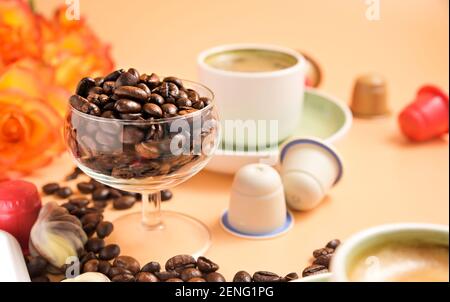 Capsules pour machine à espresso . Café italien aromatique dans une tasse et bouquet de roses . Grains de café Arabica pour la préparation d'une boisson traditionnelle . Photo de haute qualité. Copier l'espace Banque D'Images