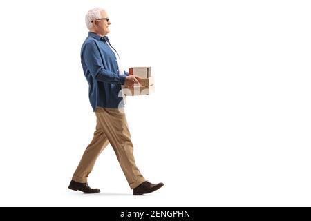 Homme mûr marchant avec une caisse avec des livres isolés sur arrière-plan blanc Banque D'Images