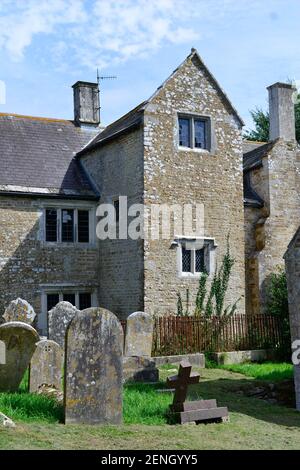 un ancien manoir en pierre avec un petit cimetière d'église au premier plan Banque D'Images