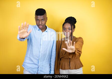 Jeune couple afro-américain debout sur fond jaune beau, belle femme, beauté, cheveux noirs, fond bleu, origine ethnique caucasienne Banque D'Images