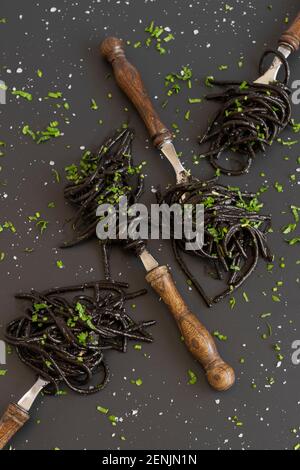 Pâtes à spaghetti noires à l'encre de tatillefish. Pâtes de fruits de mer noires sur fond sombre. Cuisine méditerranéenne fine. Banque D'Images