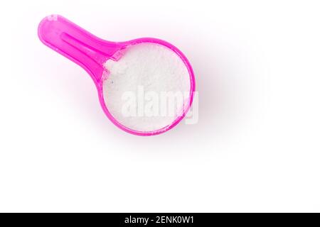 vue de dessus de la poudre à laver dans une cuillère de mesure rose isolée sur fond blanc. Photo de haute qualité Banque D'Images