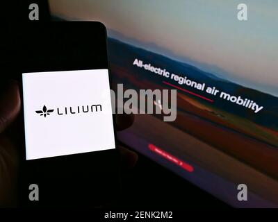 Personne tenant un smartphone avec le logo du fabricant allemand d'avions Lilium GmbH (Lilium Jet) sur l'écran devant le site. Mise au point sur l'affichage du téléphone. Banque D'Images