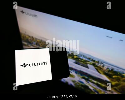 Personne tenant un téléphone portable avec le logo du fabricant allemand d'avions Lilium GmbH (Lilium Jet) à l'écran devant la page web. Mise au point sur l'affichage du téléphone. Banque D'Images