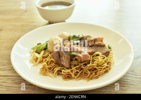 Nouilles aux œufs jaunes chinoises avec garniture de porc braisé et boule assiette avec os dans une tasse à soupe d'herbes brunes Banque D'Images