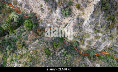 Vue aérienne du drainage acide d'une mine de cuivre abandonnée dans la région de Kalavasos, Chypre. La couleur rouge impaire du flux provient de niveaux élevés de sulfurique Banque D'Images