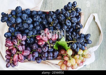 Différentes variétés de raisins dans une boîte en bois, vue de dessus. Banque D'Images