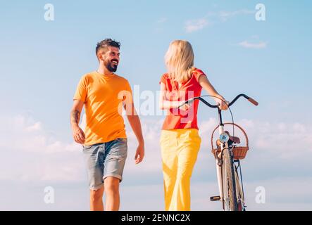 Jeune couple à pied. Les gens marchent. Des amis heureux sur la nature en plein air. Concept de loisirs et de style de vie. Jeune femme avec vélo d'époque dans une route de campagne. Banque D'Images