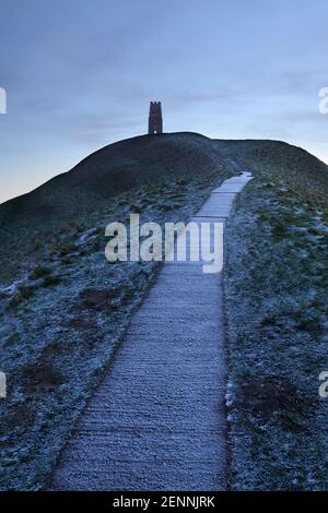 La tour St Michael's Tower au sommet de Glastonbury Tor, prise depuis le fond du chemin qui l'mène le matin d'hiver froid avant le lever du soleil. Banque D'Images