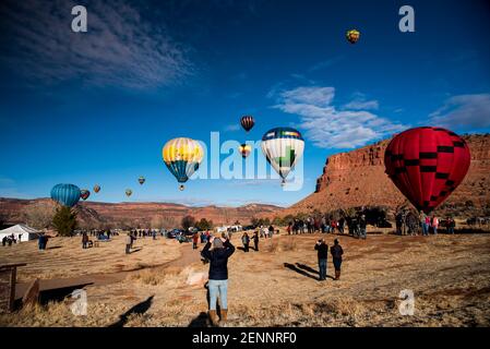 Kanab, Utah, États-Unis, 19 février 2021 - des spectateurs se rassemblent pour observer 30-40 ballons d'air chaud s'élever au-dessus des falaises rouges et du ciel bleu de Kanab, Utah, États-Unis. Banque D'Images