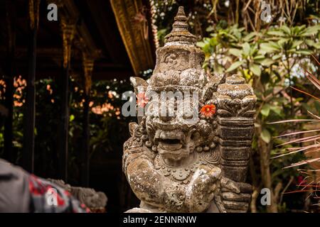 Un gardien de porte (dvarapala) avec des fleurs sur ses oreilles au temple de Saraswati (palais d'Ubud) à Ubud, Bali Banque D'Images