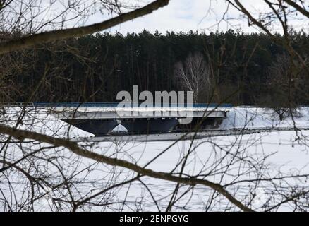 Les gens marchent le long d'un long pont au-dessus d'une rivière non gelée en hiver. Banque D'Images