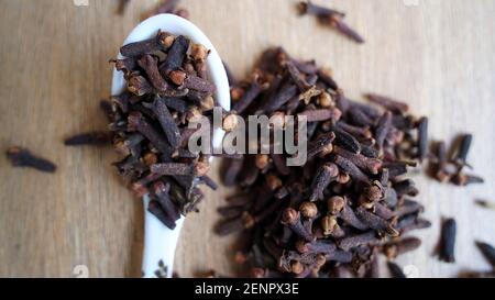 Épice de clou de girofle séché indien sur fond de table en bois. Boutons de fleurs aromatiques secs, fleurs dans une cuillère. Épices indiennes délicieuses à clous de girofle Banque D'Images