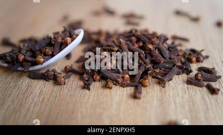 Épice de clou de girofle séché indien sur fond de table en bois. Boutons de fleurs aromatiques secs, fleurs dans une cuillère. Épices indiennes délicieuses à clous de girofle Banque D'Images