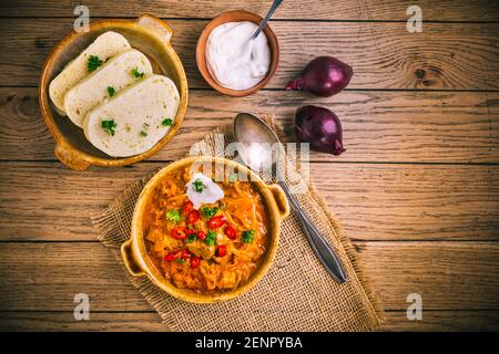 Goulash Szegedin hongrois au chou blanc mariné (choucroute), boulettes d'oignon et de pain dans une casserole Banque D'Images