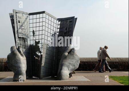 Un couple marchant par une sculpture au début de la voie côtière sud-ouest à Minehead, Somerset, Royaume-Uni. Banque D'Images