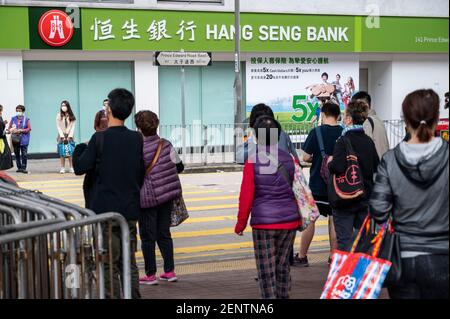 Des piétons attendent de traverser la rue en face d'une succursale de Hang Seng Bank à Hong Kong. Banque D'Images