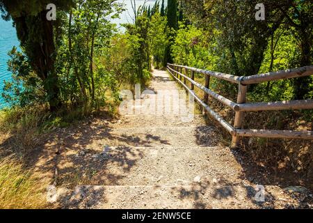 Sentier de randonnée Nature Paysage sauvage au lac de Garde, Italie sur une belle journée d'été. L'eau bleue, les rochers, les montagnes, le soleil et ciel clair. Banque D'Images