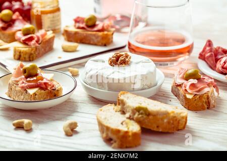 Hors-d'œuvre et sandwichs ouverts avec antipasti italiens, camembert, jambon de Parme et vin de rose sur une table en bois Banque D'Images