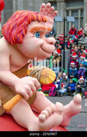 Caveman à cheval sur un mini-flotteur de dinosaure dans la célébration de la 109e édition de la Parade du Père Noël. Plus d'un demi-million de personnes suivent le même cours Banque D'Images