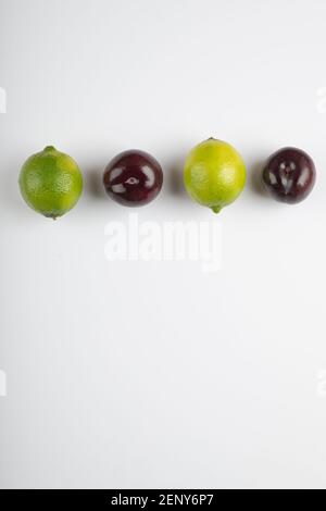 Deux fruits au citron vert et prunes fraîches sur fond blanc Banque D'Images