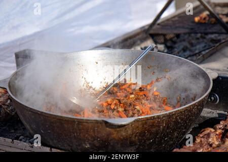 Pilaf préparer dans un chou-fleur sur un feu. Carottes grillées et viande. Comme une étape dans la préparation du pilaf traditionnel. Banque D'Images