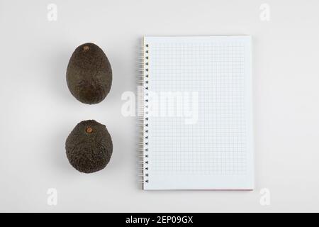 Deux délicieux avocats frais avec un carnet sur fond blanc-gris Banque D'Images