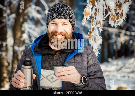 homme buvant du thé chaud dans la forêt d'hiver Banque D'Images