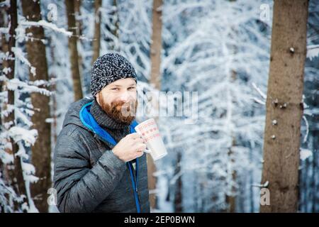 homme buvant du thé chaud dans la forêt d'hiver Banque D'Images