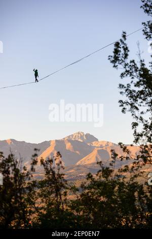 Slackliner qui se promore sur Gran Sasso avec des arbres au premier plan Banque D'Images