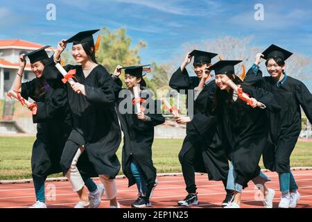 heureux étudiants de remise des diplômes et de course au stade à l'école Banque D'Images