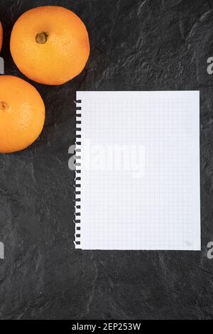 Fruits orange sains avec une feuille de papier vide table noire Banque D'Images