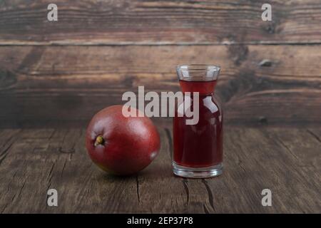 Mangue entière et verre de jus frais sur table en bois Banque D'Images