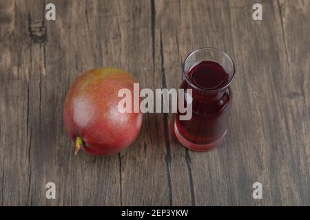 Mangue entière et verre de jus frais sur table en bois Banque D'Images