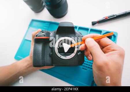 Gros plan des mains de l'homme nettoyant une matrice de caméra avec un nettoyant pour capteur de caméra ou un écouvillon de nettoyage. Entretien de l'équipement de photographie Banque D'Images