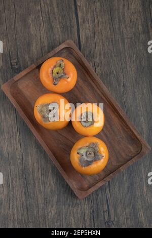 Assiette de fruits fuyu persimmon savoureux sur une surface en bois Banque D'Images