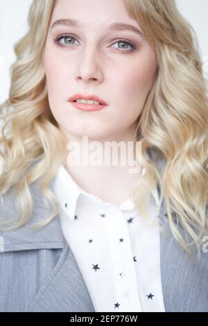 Portrait d'une belle blonde femme d'affaires sur un blanc arrière-plan dans un gilet gris et un chemisier regardant le appareil photo Banque D'Images