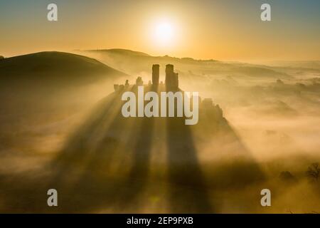 Corfe Castle, Dorset, Royaume-Uni. 27 février 2021. Météo Royaume-Uni. Un lever de soleil spectaculaire avec l'ombre des tours en ruines sur la brume entourant le château de Corfe à Dorset, un matin froid et gelé à l'aube. Crédit photo : Graham Hunt/Alamy Live News Banque D'Images