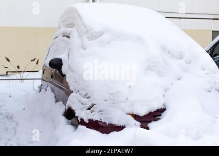 voiture rouge abandonnée en hiver garée sous une grande couche de neige par une journée ensoleillée et froide Banque D'Images