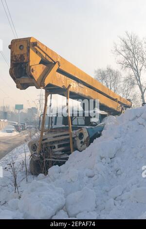 ancienne grue rouillée avec flèche jaune recouverte de neige par temps froid d'hiver Banque D'Images