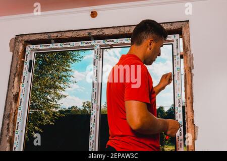 Dolyna, Ukraine 31 juillet 2020 : un employé installe un cadre de fenêtre, en installant une fenêtre en plastique. Banque D'Images