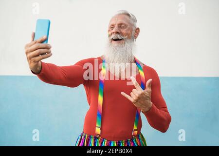 Homme gay senior utilisant le téléphone mobile lors de la manifestation de fierté lgbt - Focus sur le visage Banque D'Images