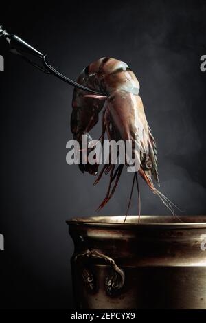 Les crevettes tigrées fraîches sont placées dans une vieille casserole d'eau chaude. Banque D'Images