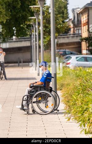 homme handicapé assis dans son fauteuil roulant devant la gare Vichy France Banque D'Images
