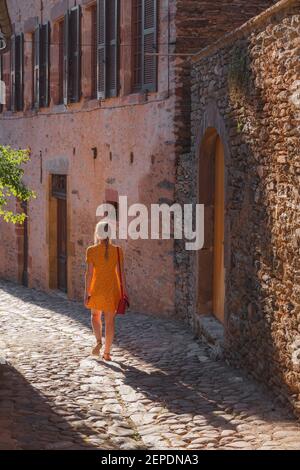 Une jeune touriste féminine en robe d'été explore une ruelle de campagne dans le charmant et pittoresque village médiéval français de Conques, l'Aveyron Occitanie Fran Banque D'Images