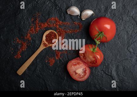 Vue de dessus des tomates mûres entières ou coupées à moitié avec ail et piment rouge Banque D'Images