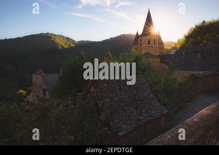 Lever de soleil ou coucher de soleil doré au-dessus du pittoresque et charmant village médiéval français de Conques, Aveyron, et l'église abbatiale de Sainte-Foy, en Occitanie Banque D'Images