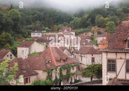 Le pittoresque et charmant village médiéval français au sommet d'une colline de Saint-Cirq-Lapopie lors d'une matinée brumeuse dans la vallée du Lot, en France. Banque D'Images