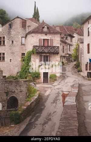 Le pittoresque et charmant village médiéval français au sommet d'une colline de Saint-Cirq-Lapopie lors d'une matinée brumeuse dans la vallée du Lot, en France. Banque D'Images