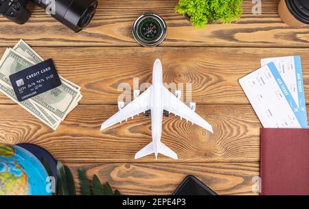 Miniature d'un avion sur une table en bois avec billets, documents, argent et autres accessoires de voyage. Concept de vacances et de réservation. Vue de dessus Banque D'Images